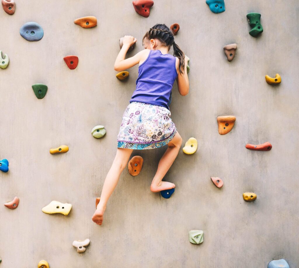 Small girl climbing a rock wall.
