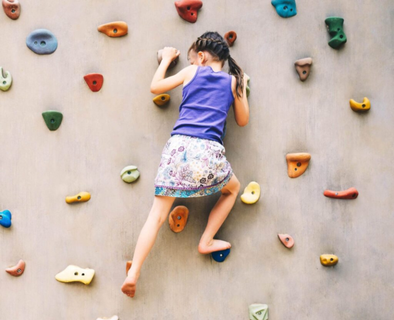 young girl climbing a rock wall