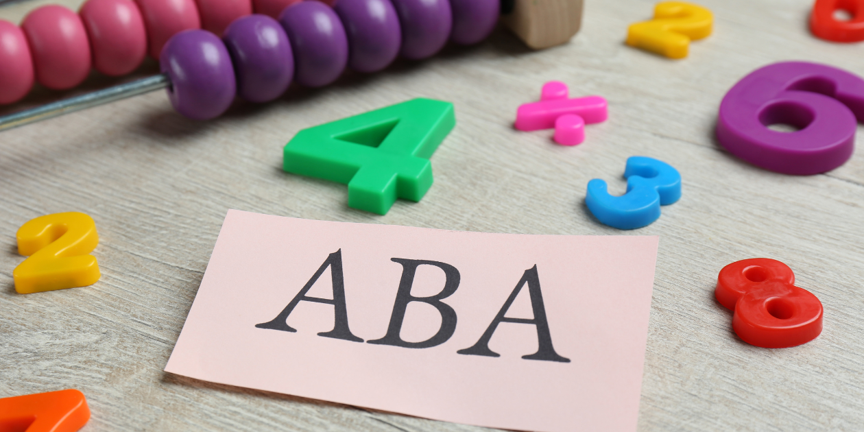 beads, letters and numbers scattered on a table with a piece of paper that reads 'ABA'