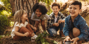 four children sitting in nature, laughing