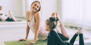 a young woman introducing a young girl to a new activity, yoga