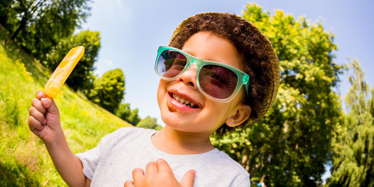 a young boy with autism eating a popsicle and wearing sunglasses