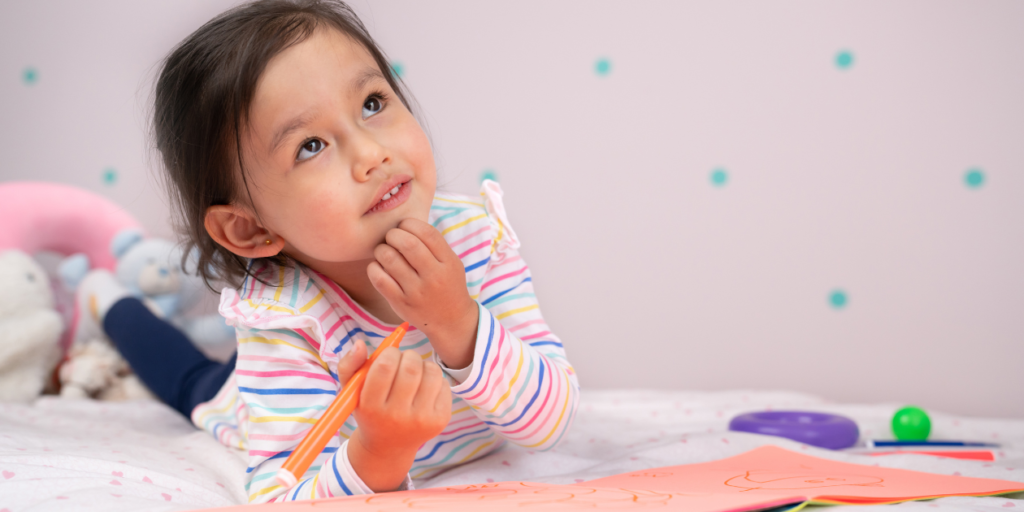 Young girl laying on her bed coloring