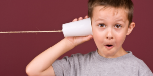 a kid with a paper cup and string to his ear, like a phone